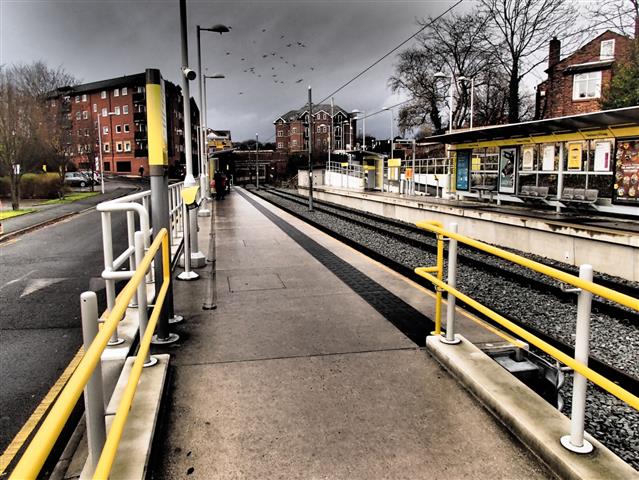 Colour-contrasted handrails on a ramp to a rail station platform in England. If this ramp were to be constructed in Canada, it would require colour-contrasting strips at the slope transition. The platform edge detail would also differ.