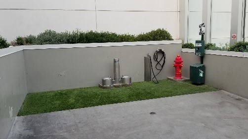 Outdoor, post-security, airport dog relief area equipped with waste receptacles, hand washing facilities, and a hose. Image provided by Designable Environments.