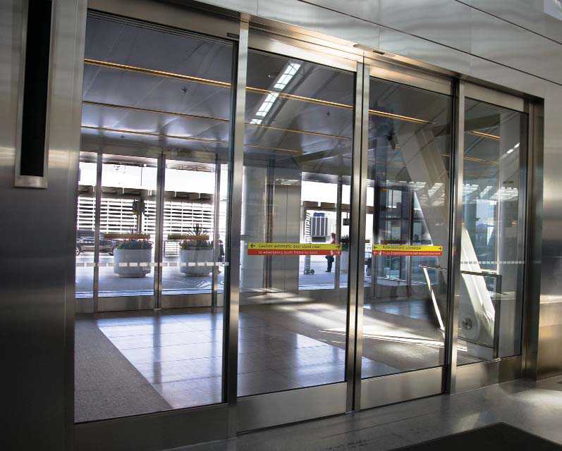 Automatic sliding doors at a building entrance with a colour-contrasted strip on the glass doors.
