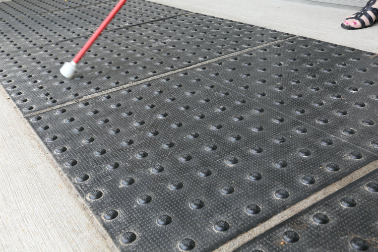 A close-up photograph of a detectable warning surface. The surface incorporate truncated domes to provide tactile warning information and is colour-contrasted with the adjacent ground finish to provide visual warning.